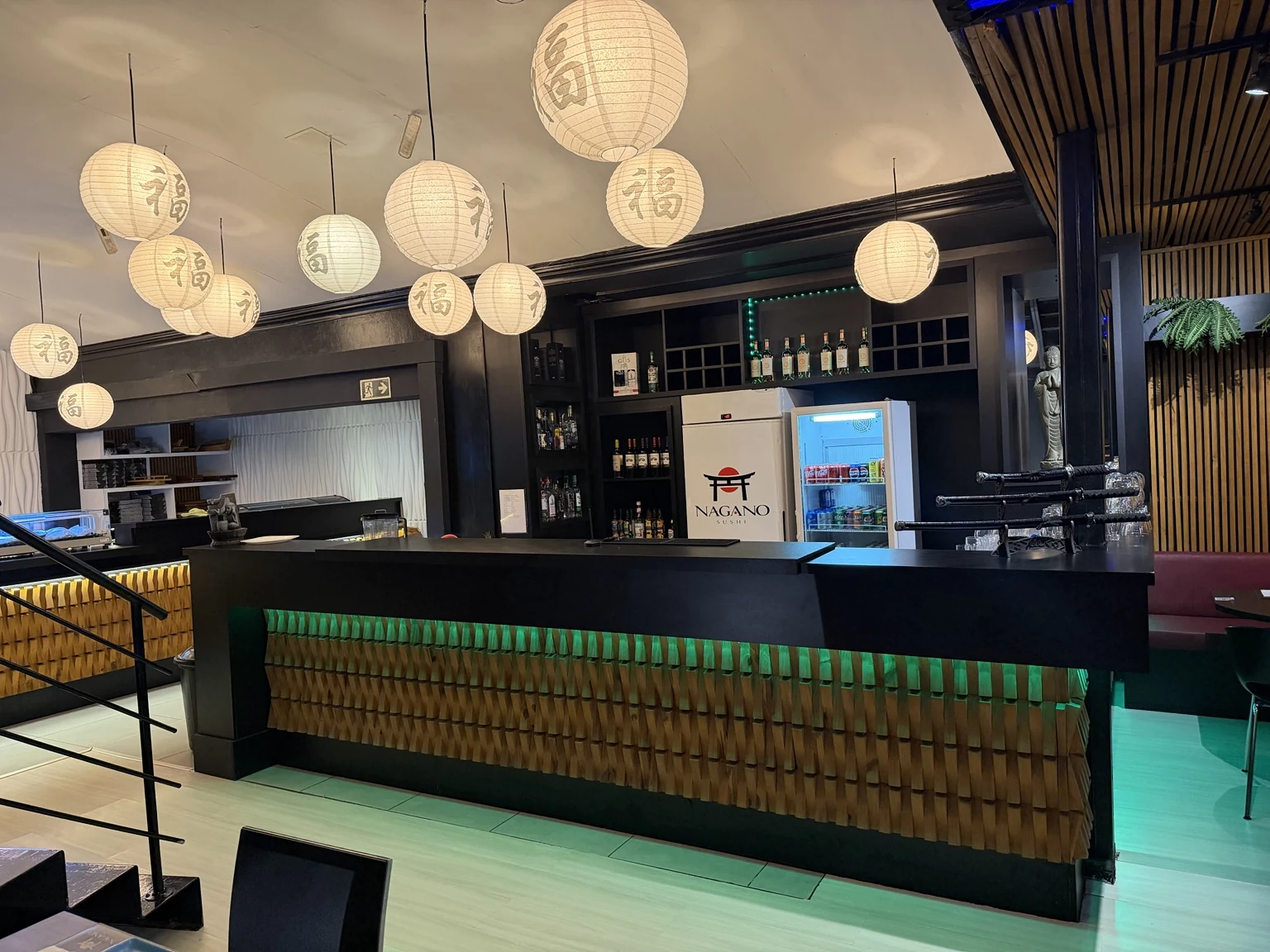 Bar do Nagano com balcão de madeira, iluminação verde e lanternas japonesas